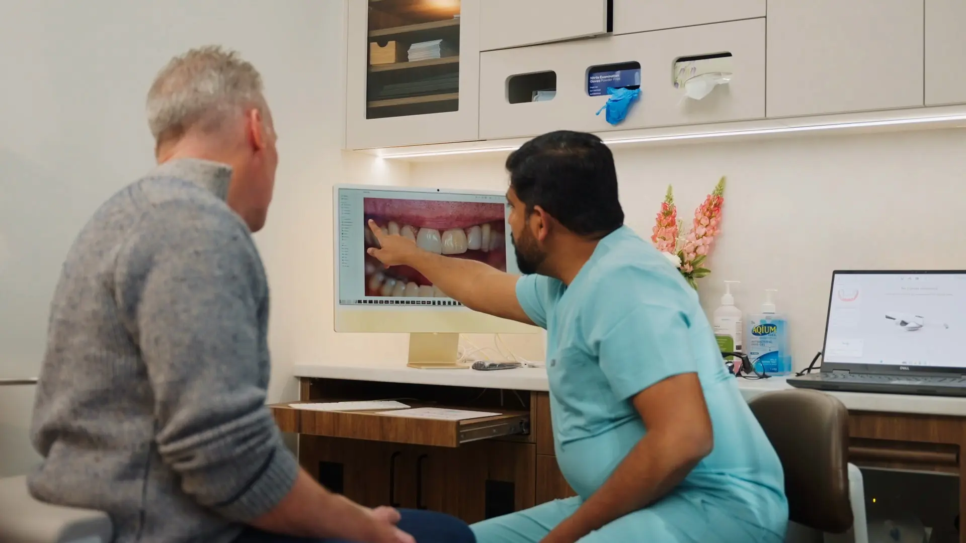 Dr Sri reviewing a patient's smile photos on a screen with them