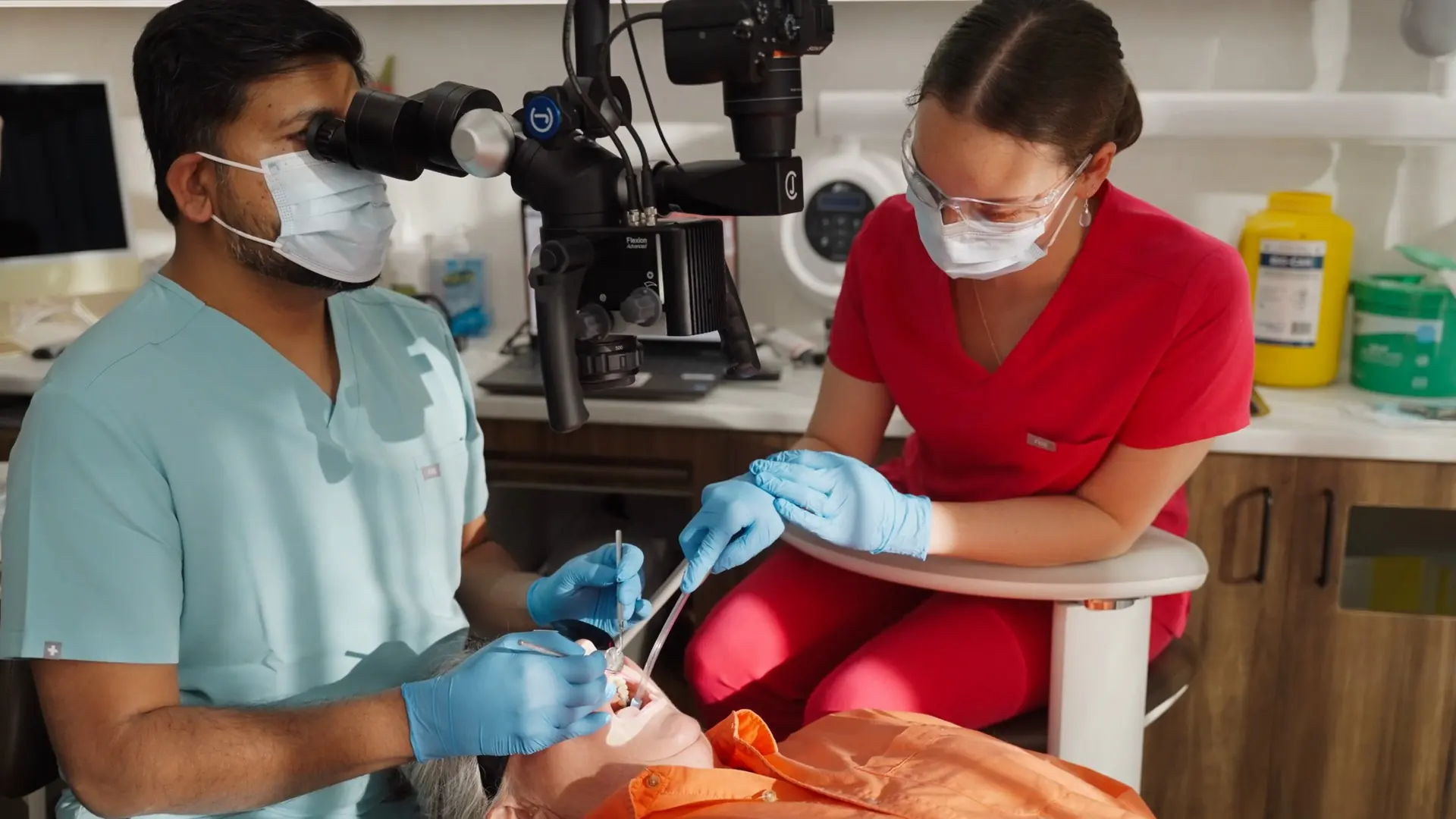 A dentist and assistant treating a patient under the microscope